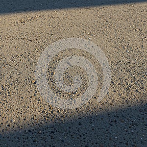 A close-up view of a concrete surface with small pebbles embedded in it. The surface