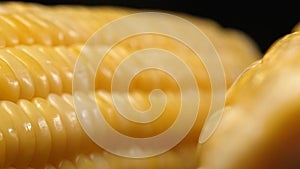 Close-up view of corn reveals a yellow kernel with black background. Comestible.