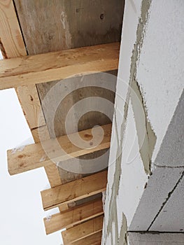 close-up view of corner of house with scaffolding, where preparatory work is carried out before covering roof of final roof