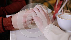 Close-up view of couple holding hands while sitting in restaurant