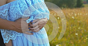 The close-up view of the couple tenderly touching hands. The man is hugging the young woman back and stroking her face