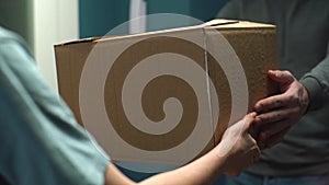 Close-up view of courier service man delivering package to client on doorstep at apartment.