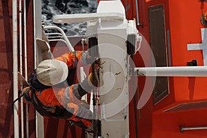 Close up view on crew member with orange jacket and white helmet