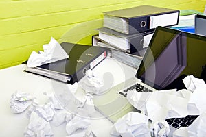 Close-up view of crumpled paper over laptop on desk with empty chair and folders