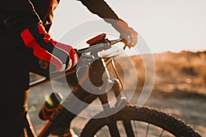 Close up view of a Cyclist equipment glove and handlebar. Man Riding the Bike Down Rocky Hill at Sunset. Extreme Sport Concept