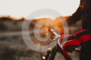 Close up view of a Cyclist equipment glove and handlebar. Man Riding the Bike Down Rocky Hill at Sunset. Extreme Sport Concept