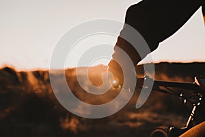 Close up view of a Cyclist equipment glove and handlebar. Man Riding the Bike Down Rocky Hill at Sunset. Extreme Sport Concept