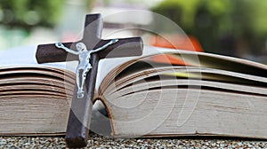 Close up view of dark brown wooden cross on old books with blur background