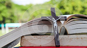 Close up view of dark brown wooden cross on old books with blur background