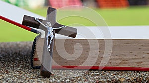 Close up view of dark brown wooden cross on old books with blur background