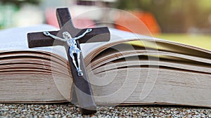 Close up view of dark brown wooden cross on old books with blur background