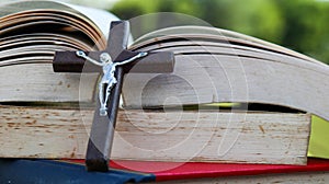 Close up view of dark brown wooden cross on old books with blur background