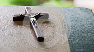 Close up view of dark brown wooden cross on old books with blur background