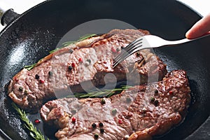 Close-up view of delicious juicy meat and fork preparing on iron pan
