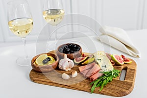 close-up view of delicious snacks on wooden board and glasses of wine on table