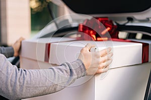 Close-up view of delivery man standing near car preparing to take parcel out of trunk of car.