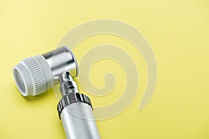 Close up view of dermatoscope on yellow background.