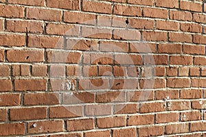 Close-up view of a deteriorating old red clay brick wall texture