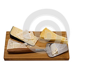 Close up view of different kinds of cheese with cheese knife isolated on wooden board.