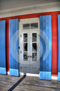 Close-up view of a door with a window with white shutters on a blue building