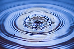 Close up view of Drops making circles on blue water surface isolated on background