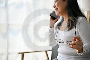 Close up view of elderly woman having a phone call while holding a glasses