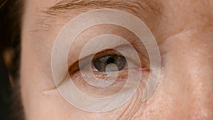 Close-up view of an elderly woman. the woman opens her eyes and looks into the camera. The skin of an elderly person