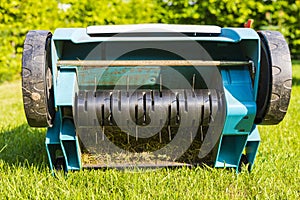 Close up view of electric lawn aerator on green grass isolated.