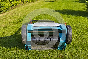 Close up view of electric lawn aerator on green grass isolated.