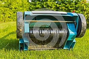 Close up view of electric lawn aerator on green grass isolated.