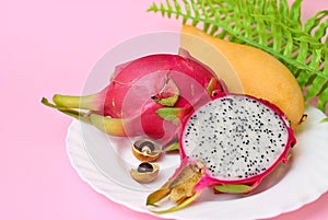 Close up view of exotic dragon fruit with mango cut and whole sliced isolated on a blue background, leafs and petals