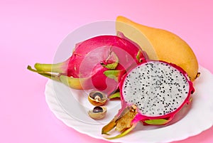 Close up view of exotic dragon fruit with mango cut and whole sliced isolated on pink background with leafs and petals
