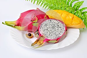 Close up view of exotic dragon fruit with mango cut and whole sliced isolated on white background with leafs and petals