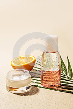 close up view of facial cream and lotion palm leaf and orange half with water drops