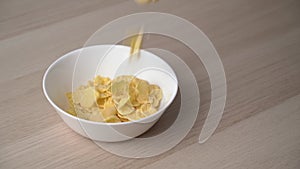 Close-up view of a falling corn flakes in a white plate.