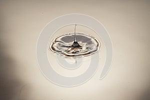 Close up view of falling drops on water surface isolated on brown background