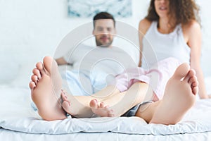 close-up view of feet of young couple on bed