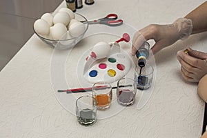 Close up view of female and child hands prepare color for painting of traditional Easter eggs.