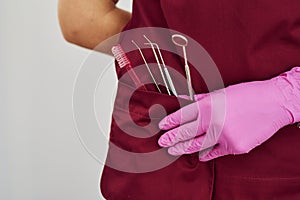 Close up view of female dentist in uniform that standing in stomatology office with tools in pocket