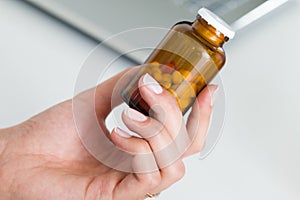 Close-up view of female doctor hand holding bottle with pills