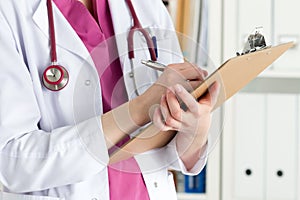 Close up view of female doctor hands filling patient history