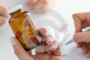 Close-up view of female doctor's hand holding bottle with pills