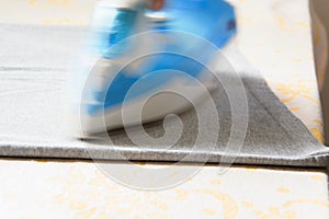 Close up view of female hand ironing a t-shirt with steam iron