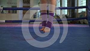 Close up view of female legs in socks jumping with skipping rope inside of the boxing ring in a fitness club. Slowmotio