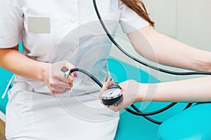 Close up view of female medicine doctor measuring blood pressure to her patient. Hands close up. Healthcare, healthy lifestyle and