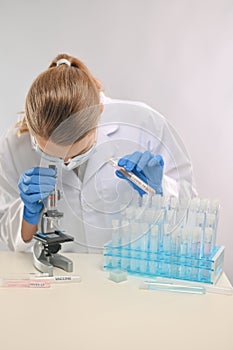 Close-up view of female microbiologist in biohazard protective clothing look at microscope for explore covid-19 vaccine. Research