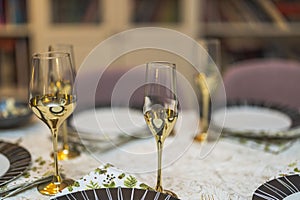 Close up view of festively set table. Gold colored wine glasses on foreground.