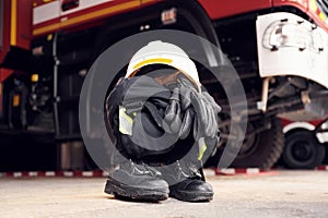 Close up view of firefighter's hat, gloves, jacket, pants and shoes. With big vehicle