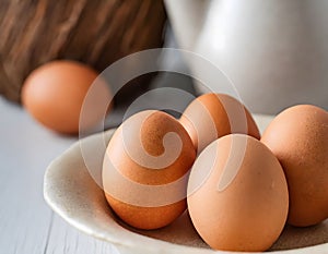 A close-up view of five brown eggs on a plate. Simplicity in nutrition - fresh brown eggs as a symbol of organic wholesomeness