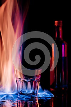 close up view of flame, empty glass and bottle of sambuca alcohol drink